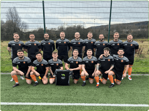 A image of the Glenifer Thistle first team typical football team photo with 2 rows of players. The first row kneels the second row stands. In the middle there is a t-shirt with Down To Earth Garden Services sponsoring Glenifer Thistle.