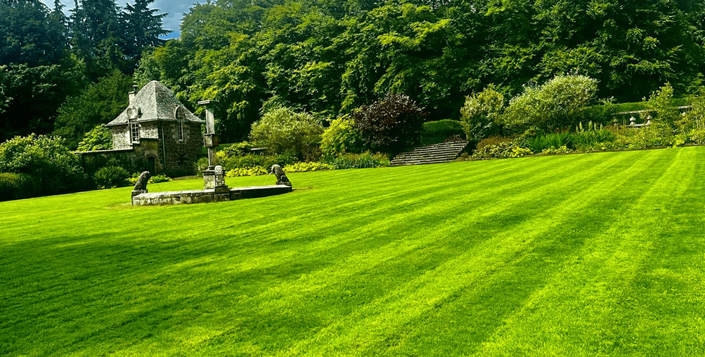 A big long image of a beautiful stately garden been cut really well with a water well to the left