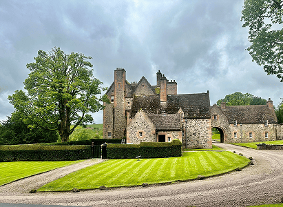 This is a picture of a stately home with beautiful cur grass and gravel stones and trees around the property