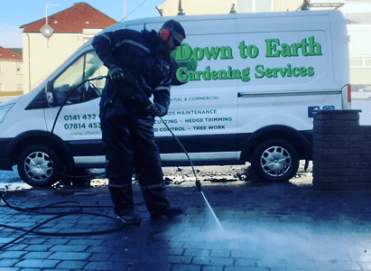 This is an image of the down to earth garden services team pressure washing a driveway cleaning all the hard to get debris